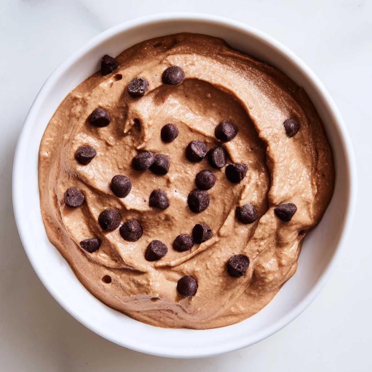 Rich, dark-chocolate Chocolate Hummus is swirled in a bowl, ready to be enjoyed as a snack or dessert.