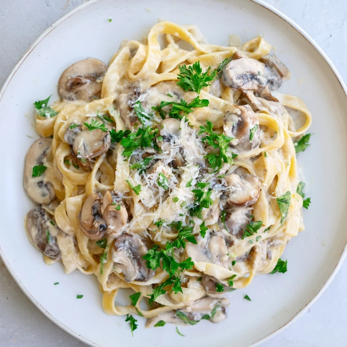 Steaming Creamy Mushroom Alfredo in a skillet with al dente fettuccine and Parmesan.  