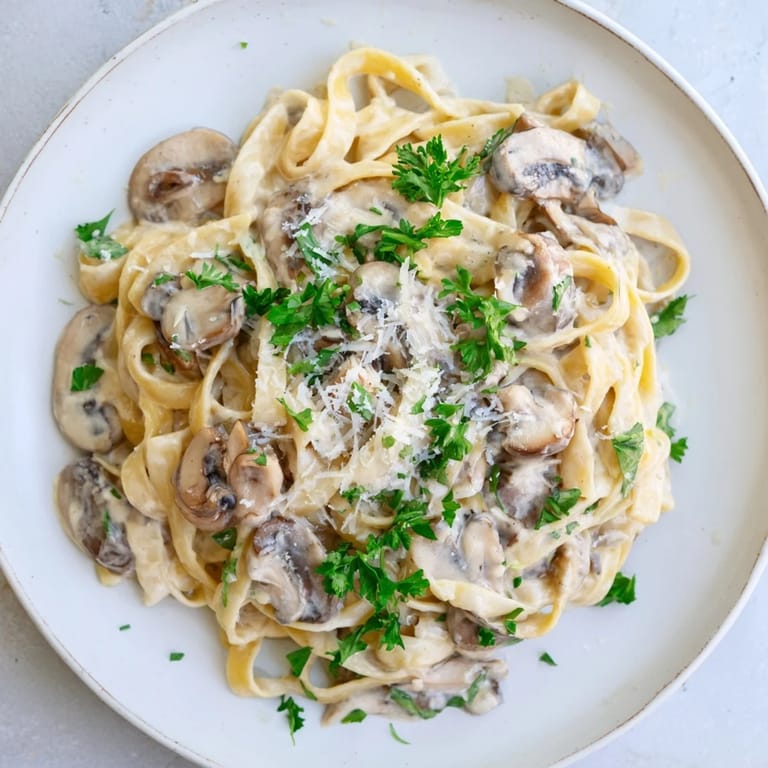 Steaming Creamy Mushroom Alfredo in a skillet with al dente fettuccine and Parmesan.  
