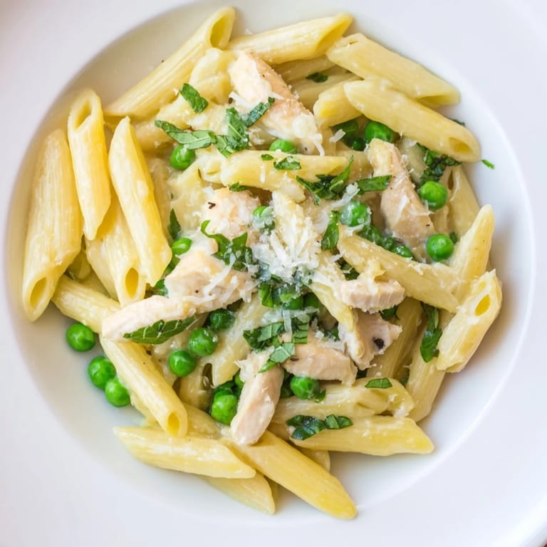 Served in a rustic white bowl, this easy Pea & Mint Chicken Pasta recipe features tender chicken, sweet peas, and a light lemony sauce.
